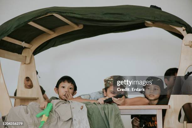 rollenspiel von thai niedlichen kindern spielen spiel soldat mit einem freund in der schule - children role playing crime stock-fotos und bilder