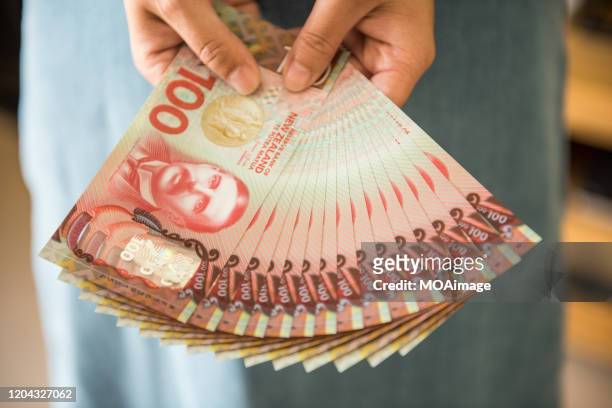 woman holding fanned out new zealand money - new zealand money stockfoto's en -beelden