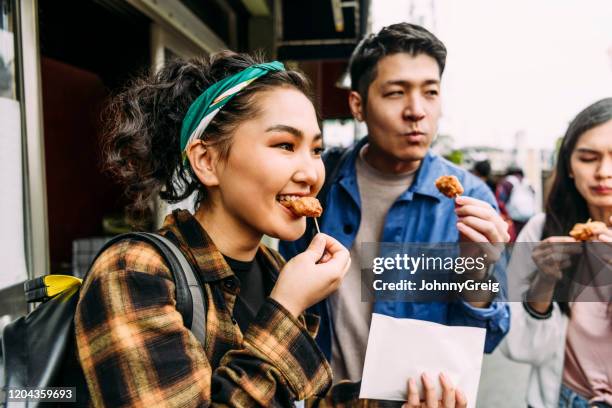 vrolijke jonge vrouw die straatvoedsel met vrienden eet - explore stockfoto's en -beelden