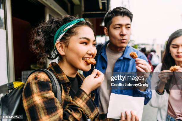 cheerful young woman eating street food with friends - provar imagens e fotografias de stock