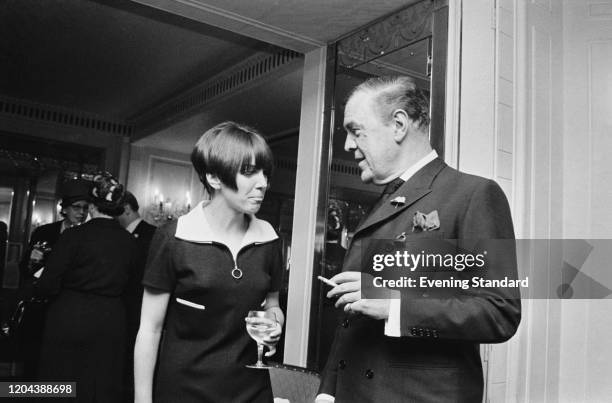 English fashion designer and fashion icon Mary Quant chatting with British fashion designer Norman Hartnell at a party, UK, 21st April 1966.