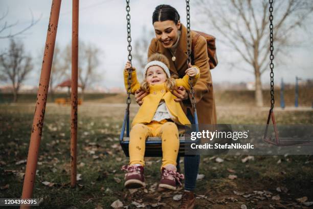 mother and daughter on swing, having fun - playground equipment happy parent stock pictures, royalty-free photos & images