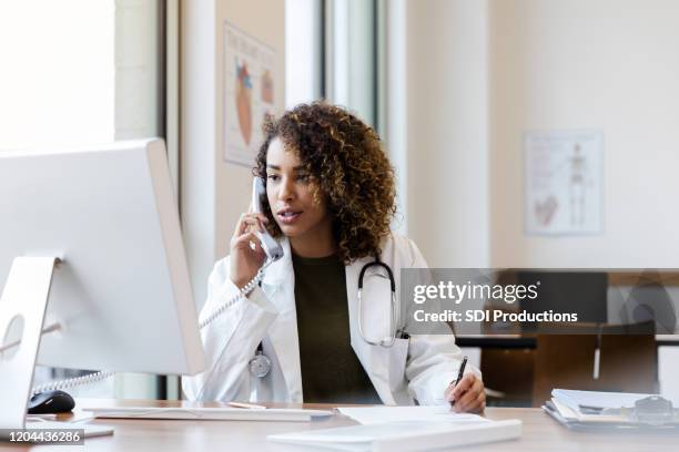 mid adult female doctor calls about exam results - telefonberatung stock-fotos und bilder