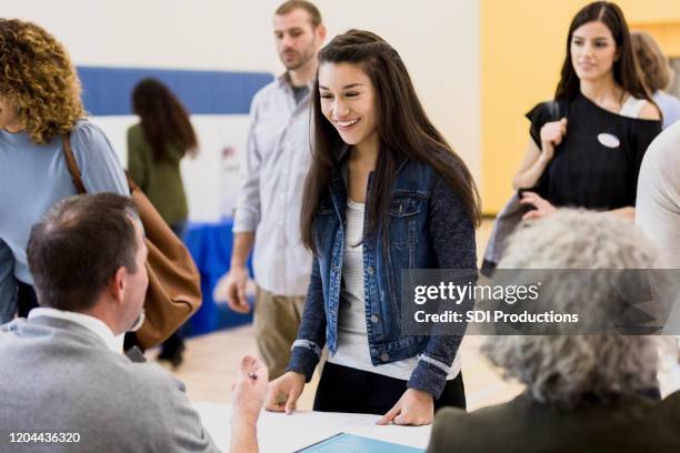 young woman signing up to vote smiles at volunteer - voting stock pictures, royalty-free photos & images