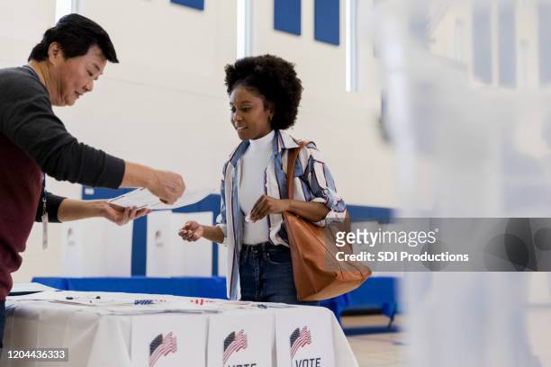 de rijpe mannelijke vrijwilliger verklaart stemdocument aan jonge vrouw - young voters stockfoto's en -beelden