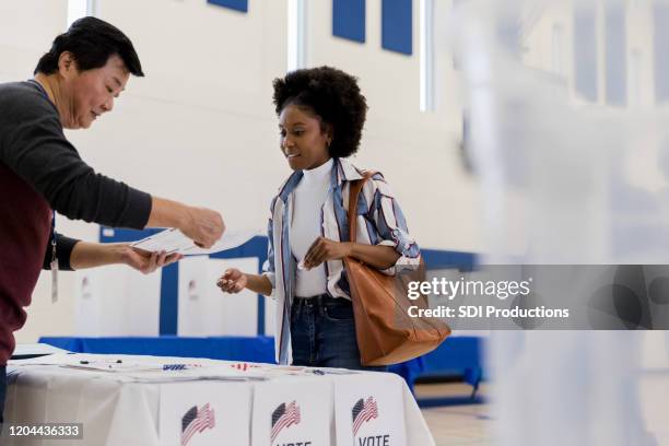 mature male volunteer explains voting document to young woman - voting stock pictures, royalty-free photos & images