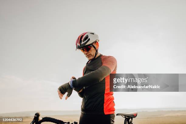 fietser die de wedstrijdtijd controleert - triathlete stockfoto's en -beelden
