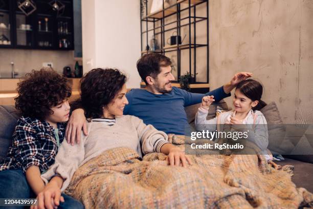 familienzeit auf dem gemütlichen sofa - blanket stock-fotos und bilder