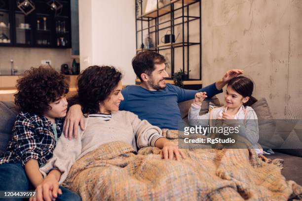 family time on the cozy sofa - blanket stock pictures, royalty-free photos & images