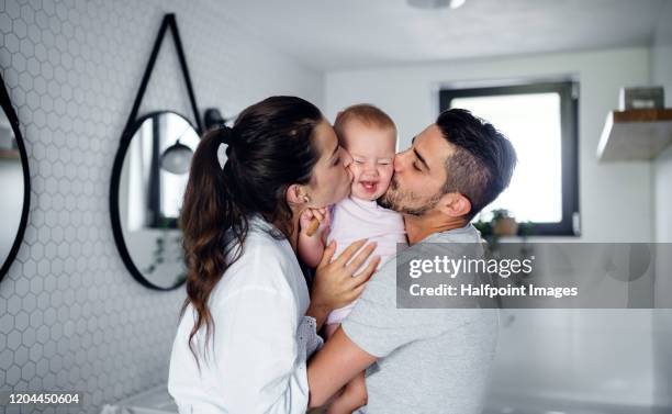 portrait of young couple with toddler girl in the morning indoors in bathroom at home, kissing. - babe fotografías e imágenes de stock