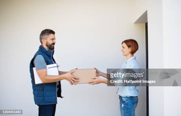 man courier delivering parcel to a young woman. - passes photos et images de collection