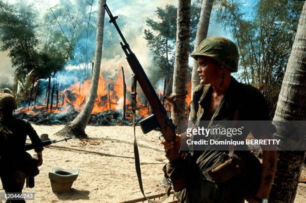 Viet Nam War in 1965 - American soldiers in a burning village.