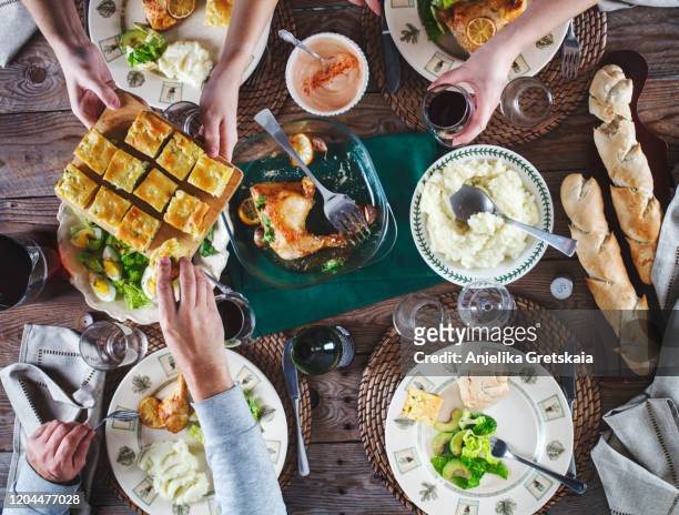 family dinner. friens dinner. flat-lay of eating and drinking peoples hands over dinning table with roasted chicken legs, mashed potatoes, salad, pie and bread - man eating pie stock pictures, royalty-free photos & images