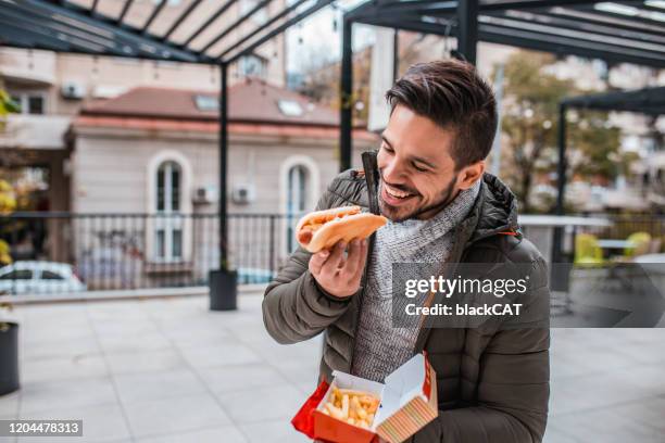 young man eating fast food - asian eating hotdog stock pictures, royalty-free photos & images