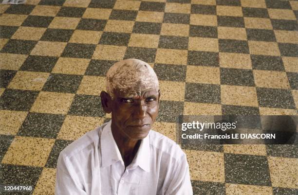 India - Portrait of a man who has just shaved his head in a ritual ceremony, on a background of squares, at Tiruchendur, Tamil Nadu.