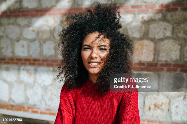 portrait of woman with afro hair looking at camera - afro frisur stock-fotos und bilder