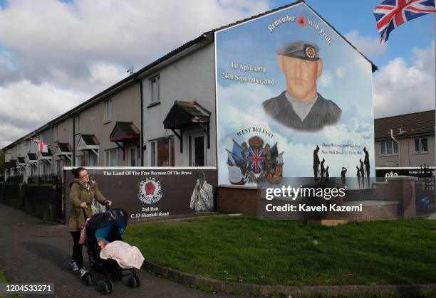 Woman pushes a pram going past the memorial site of Stevie McKeag also known as Top-Gun who was a Loyalist paramilitary commander of Ulster Defence...