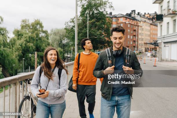 smiling friends walking on street while exploring city during vacation - stockholm ストックフォトと画像