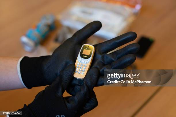 Prison officer examines a confiscated mobile phone used to smuggle drugs into HMP Liverpool, also known as Walton Prison. The prison was given a...