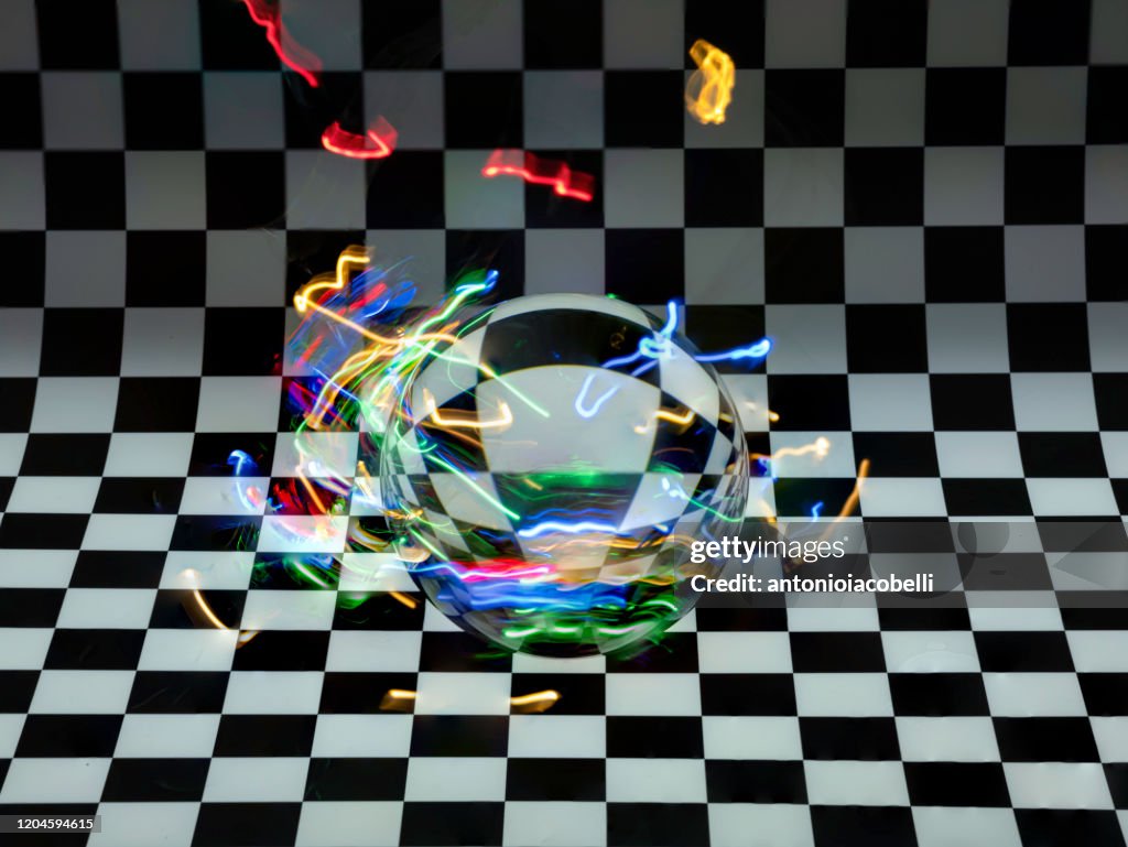 Glass sphere on a checked background with an electrostatic discharge