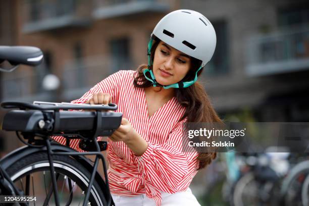 young woman changing battery pack on bicycle - ebike stockfoto's en -beelden