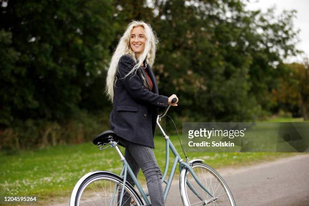 young woman with bicycle - weiblichkeit stock-fotos und bilder