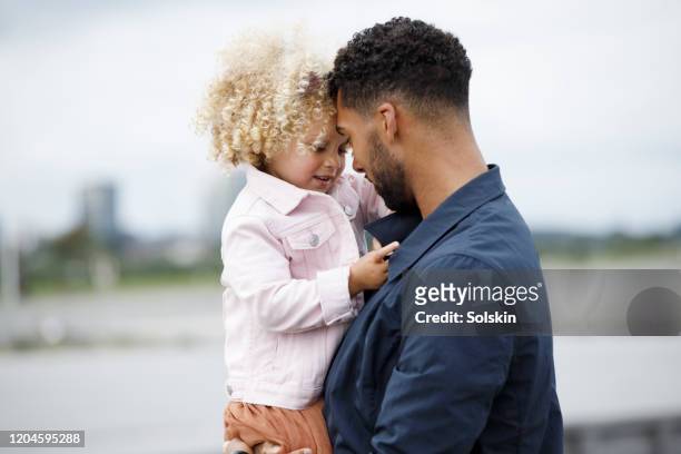 father holding daughter on arm - leanincollection father photos et images de collection