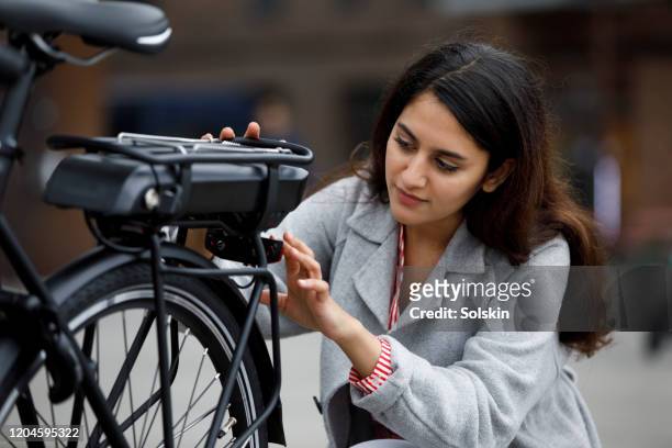 young woman changing battery pack on bicycle - ebike stock pictures, royalty-free photos & images
