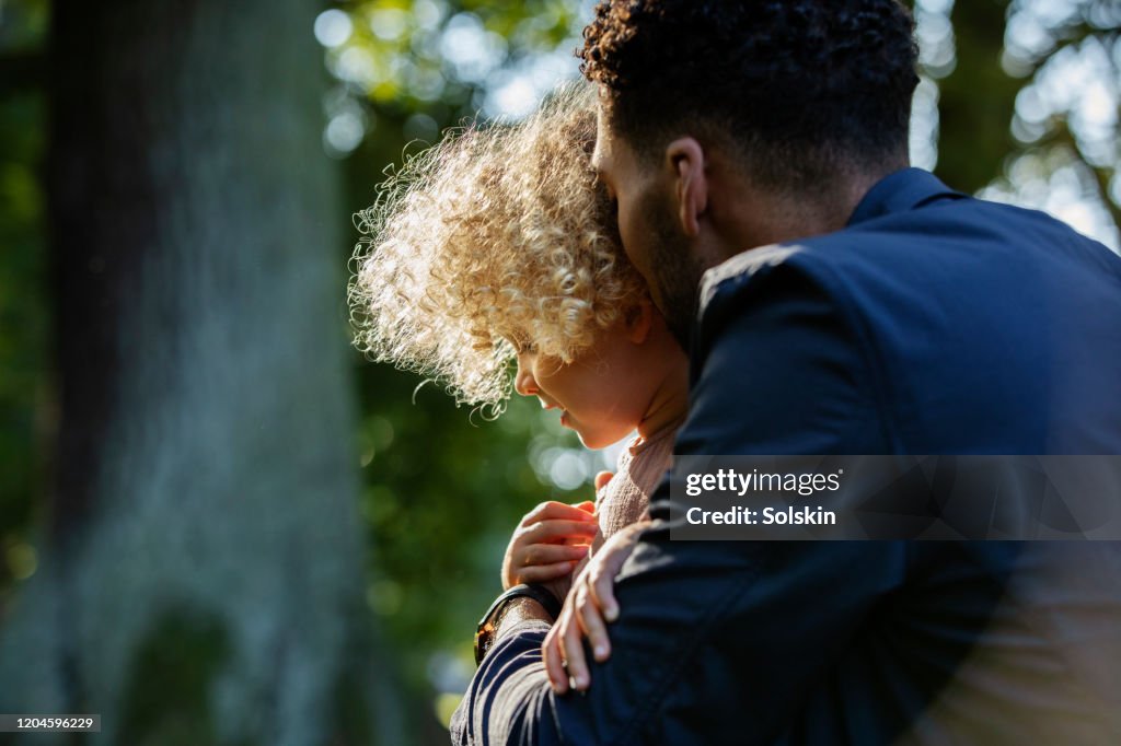 Father embracing young daughter in park area