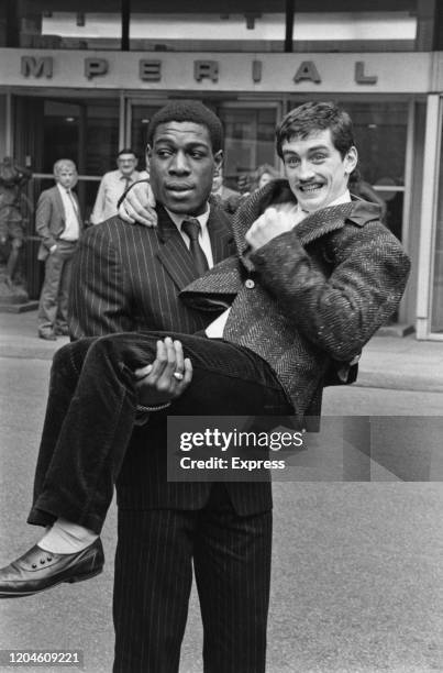 British heavyweight boxer Frank Bruno carrying Irish featherweight boxer Barry McGuigan, who has his left hand clenched into a fist, outside the...