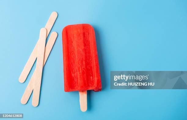 red ice lolly and sticks on blue background - bastone foto e immagini stock