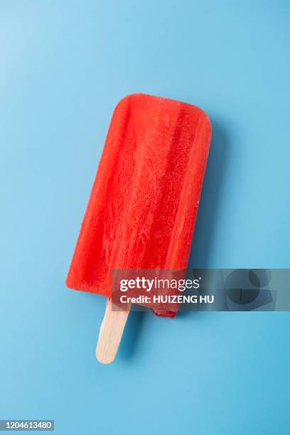 red popsicle on blue background - stieleis stock-fotos und bilder
