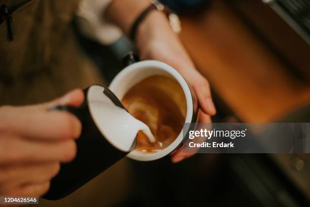 primo passo della mano barista mentre si fa un menu di bevande schiumoso - tazza di latte dall'alto foto e immagini stock