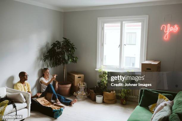 couple sitting on floor and having pizza - housewarming stock pictures, royalty-free photos & images