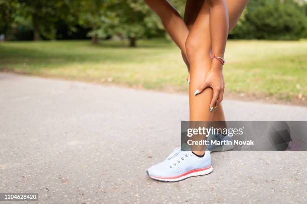 woman holding her leg due to muscle tear in calf - ふくらはぎ ストックフォトと画像