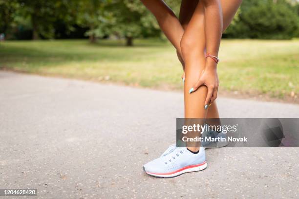 woman holding her leg due to muscle tear in calf - calves stockfoto's en -beelden