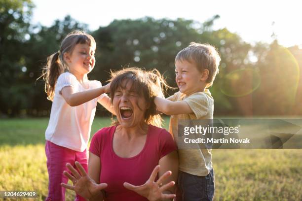 woman screams while children mess up her hair - onvolkomenheid stockfoto's en -beelden