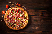 Pizza with salami, ham, bacon, garlic and fresh herbs. Rustic style.