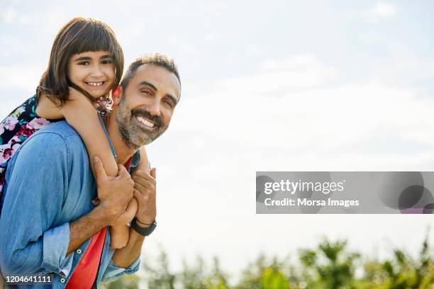 smiling father giving piggyback ride to daughter - fashionable dad stock pictures, royalty-free photos & images