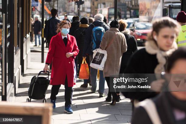 Woman wears a face mask as she walks along Camden Town high street on March 02, 2020 in London, England. There has been thirteen more reported cases...