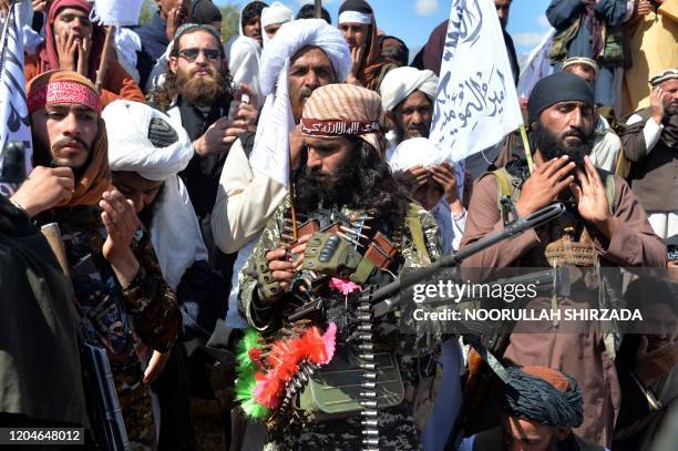 Afghan Taliban militants and villagers attend a gathering as they celebrate the peace deal and their victory in the Afghan conflict on US in...