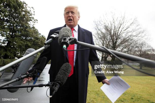 President Donald Trump holds a copy of a court document as he speaks to members of the media prior to his Marine One departure from the White House...