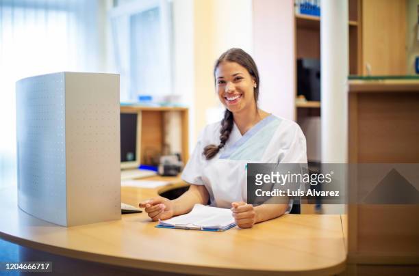 portrait of a nurse working at reception desk - bürorezeption stock-fotos und bilder