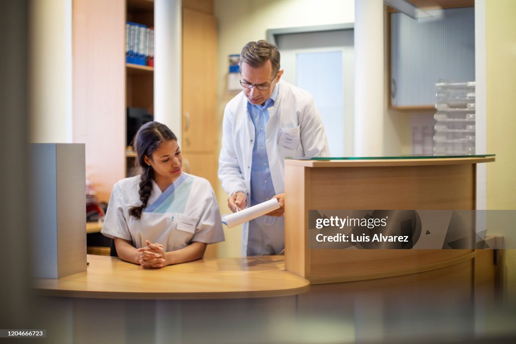 Doctor discussing patient details nurse at front desk