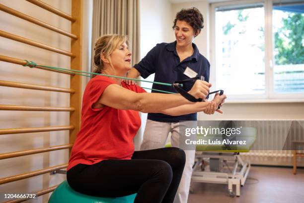 physiotherapist working on senior patient recovery in rehab - afkickcentrum stockfoto's en -beelden