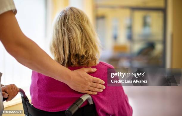 nurse helping a patient in wheelchair - pushing stockfoto's en -beelden