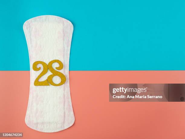 a sanitary pad with the number 28 in golden numbers on a pink and blue background - sanitary napkins stock pictures, royalty-free photos & images