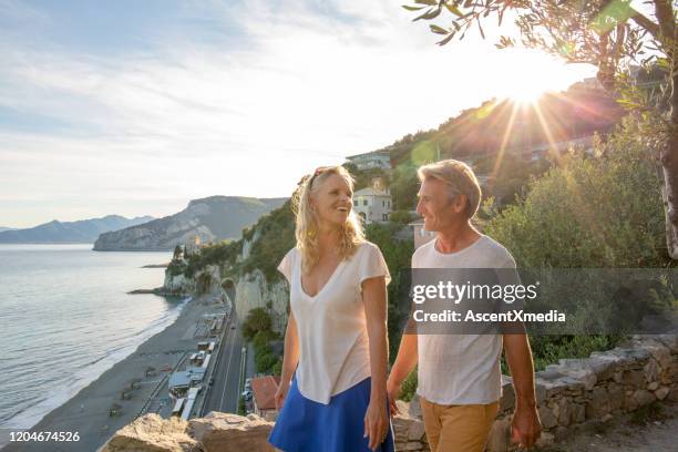 mature couple walk above coastline at sunrise - early retirement stock pictures, royalty-free photos & images