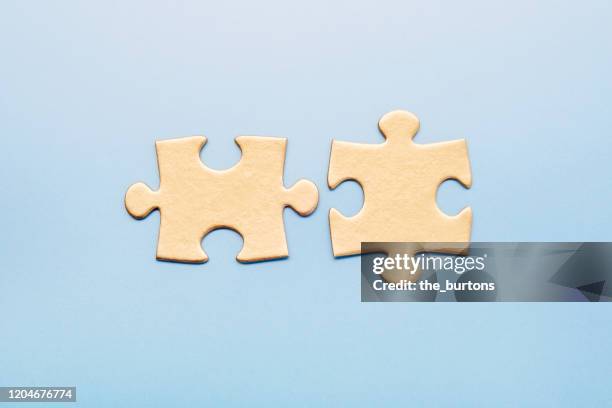 two golden puzzle pieces on blue background - puzzle imagens e fotografias de stock