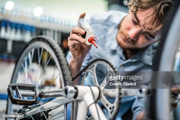 mechaniker repariert fahrradpausen in werkstatt - grease stock-fotos und bilder